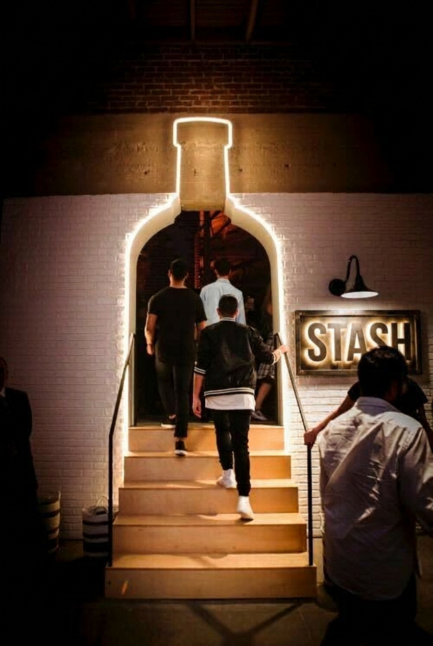 STASH entrance — guests heading up the lit bottle-arch stairway